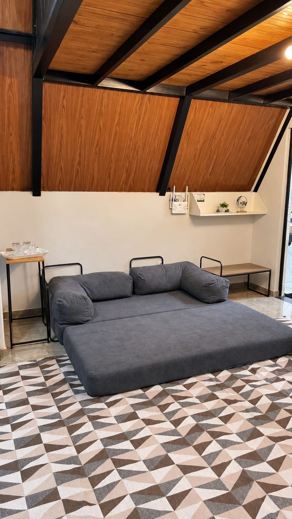 O sofá-cama da sala aberto, com roupa de cama cinza e toalhas dobradas.