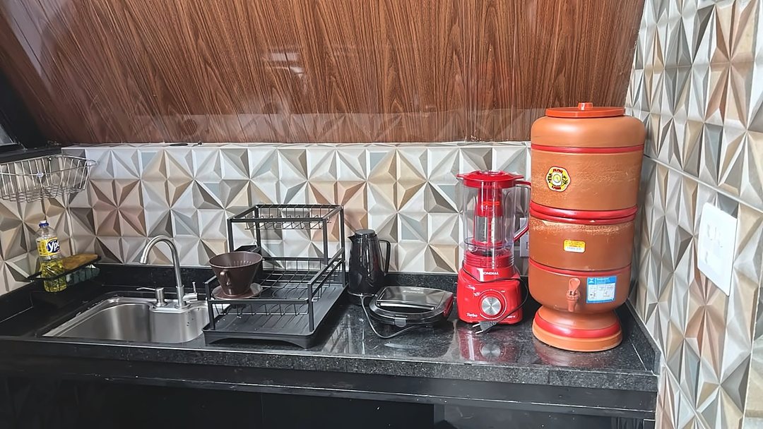 Cozinha do chalé com bancada e armários, onde ficam o cooktop de indução e o frigobar.